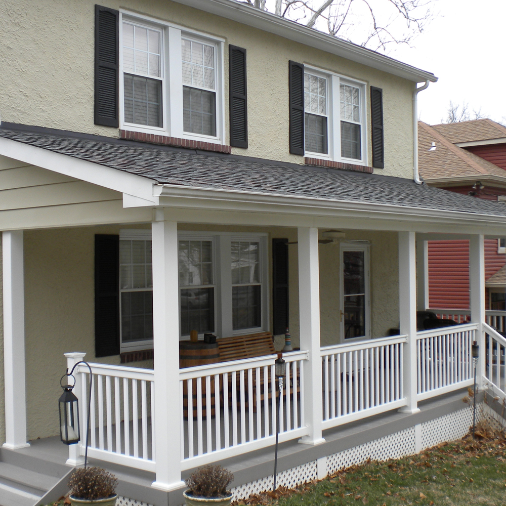 Front porch of a two story home, complete with railing.